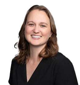 Professional headshot of a smiling woman with wavy brown hair, wearing a dark v-neck top